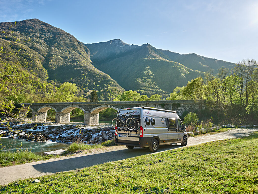 Malibu Van mit Fahrradträger fährt durch eine Landschaft