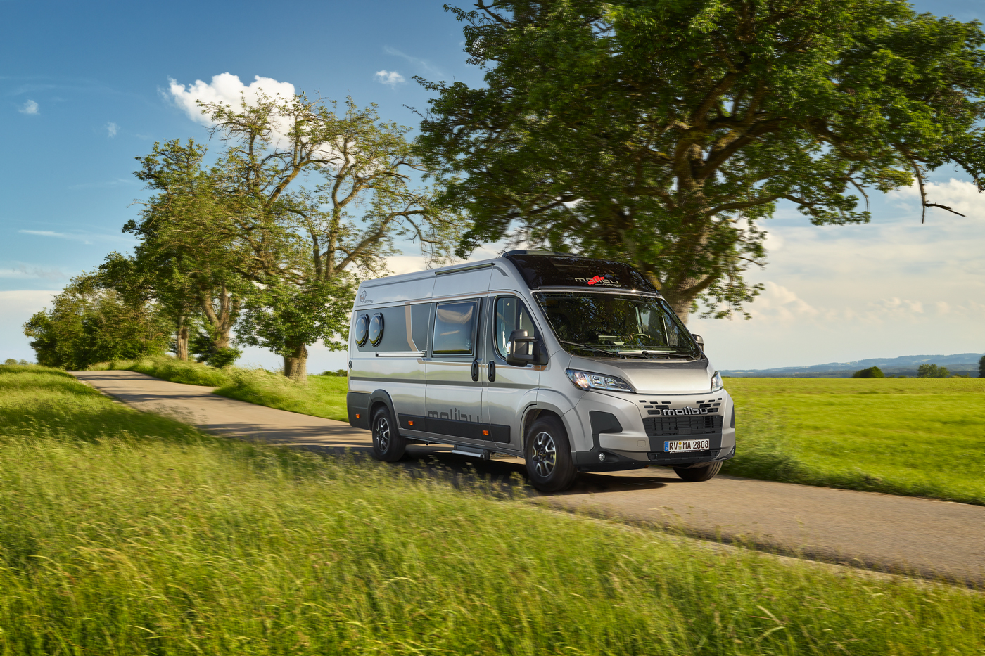 Ein Malibu Van compact 600 LE in der Farbe artensegrau metallic ist auf einer Landstraße unterwegs.