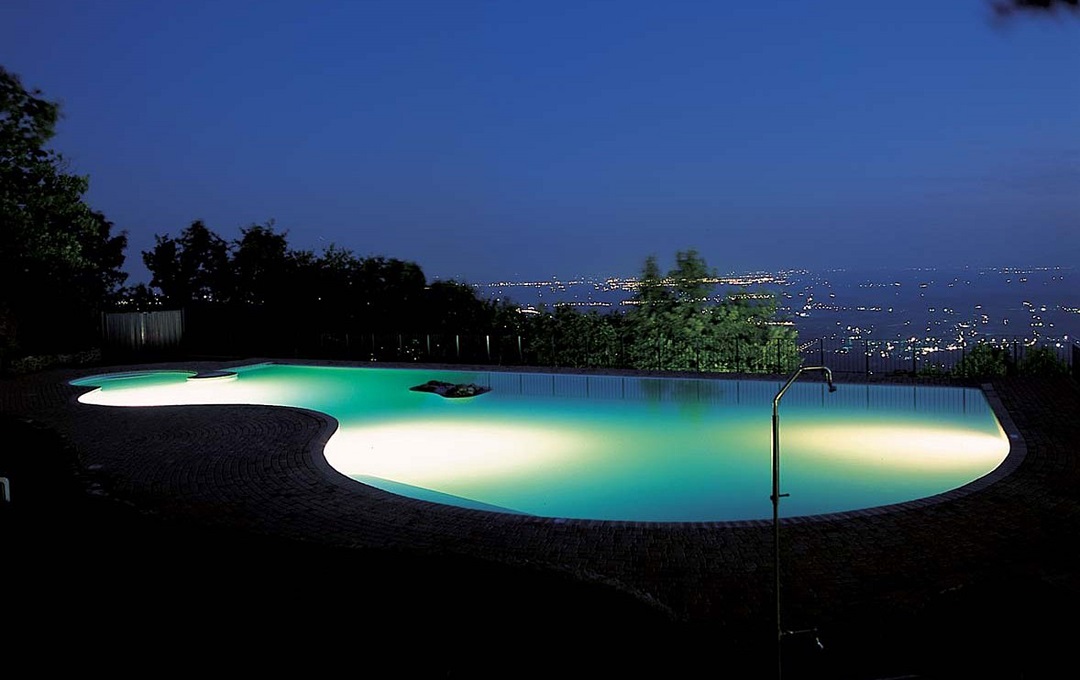 Beleuchteter Pool mit Ausblick auf die Stadt bei Nacht