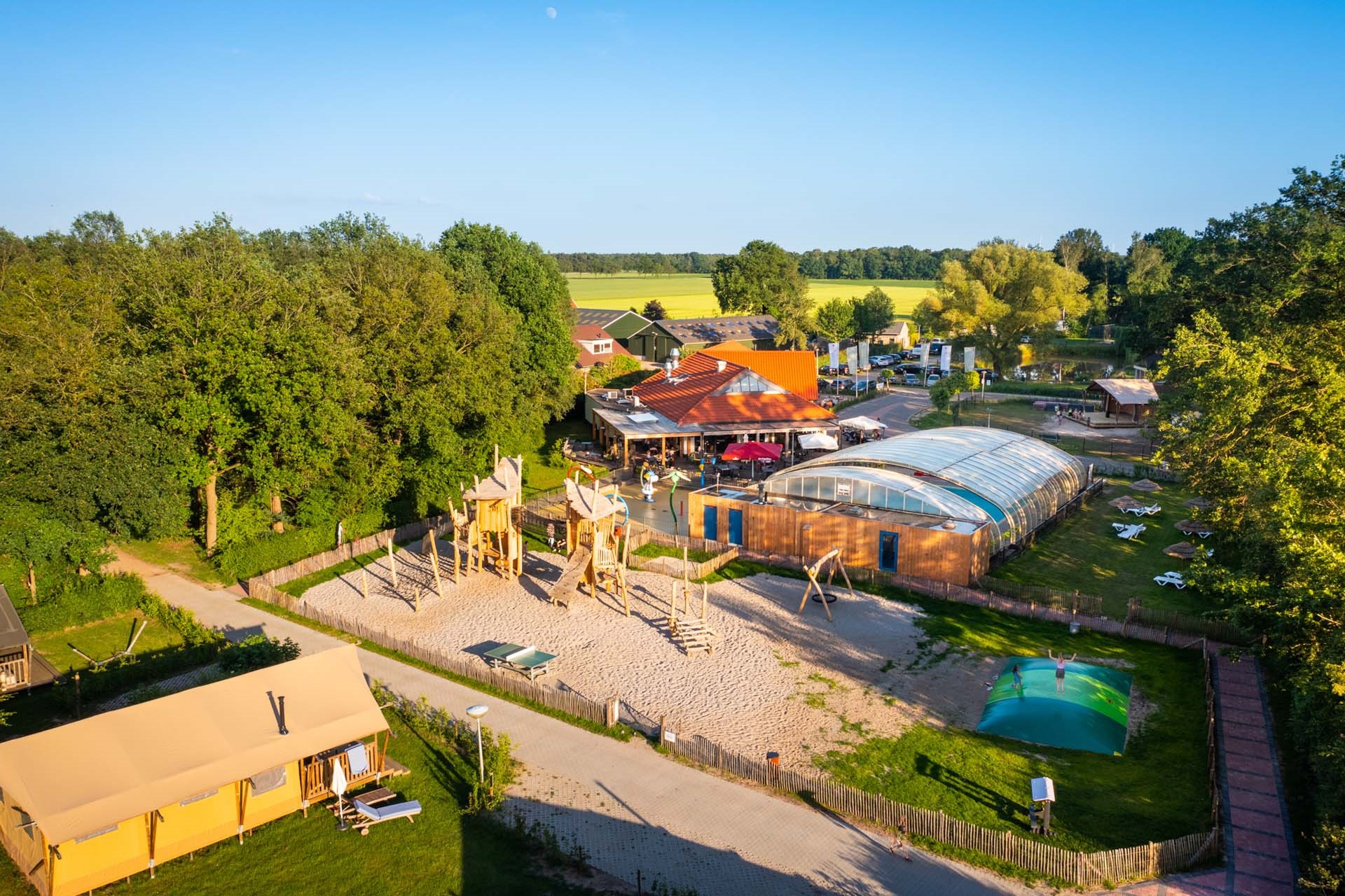 Campingplatz mit Spielplatz umgeben von Feldern und Bäumen