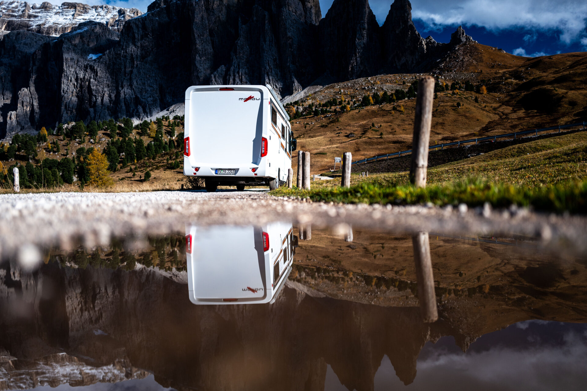 Malibu Reisemobil von hinten, hinter einem kleinen See.