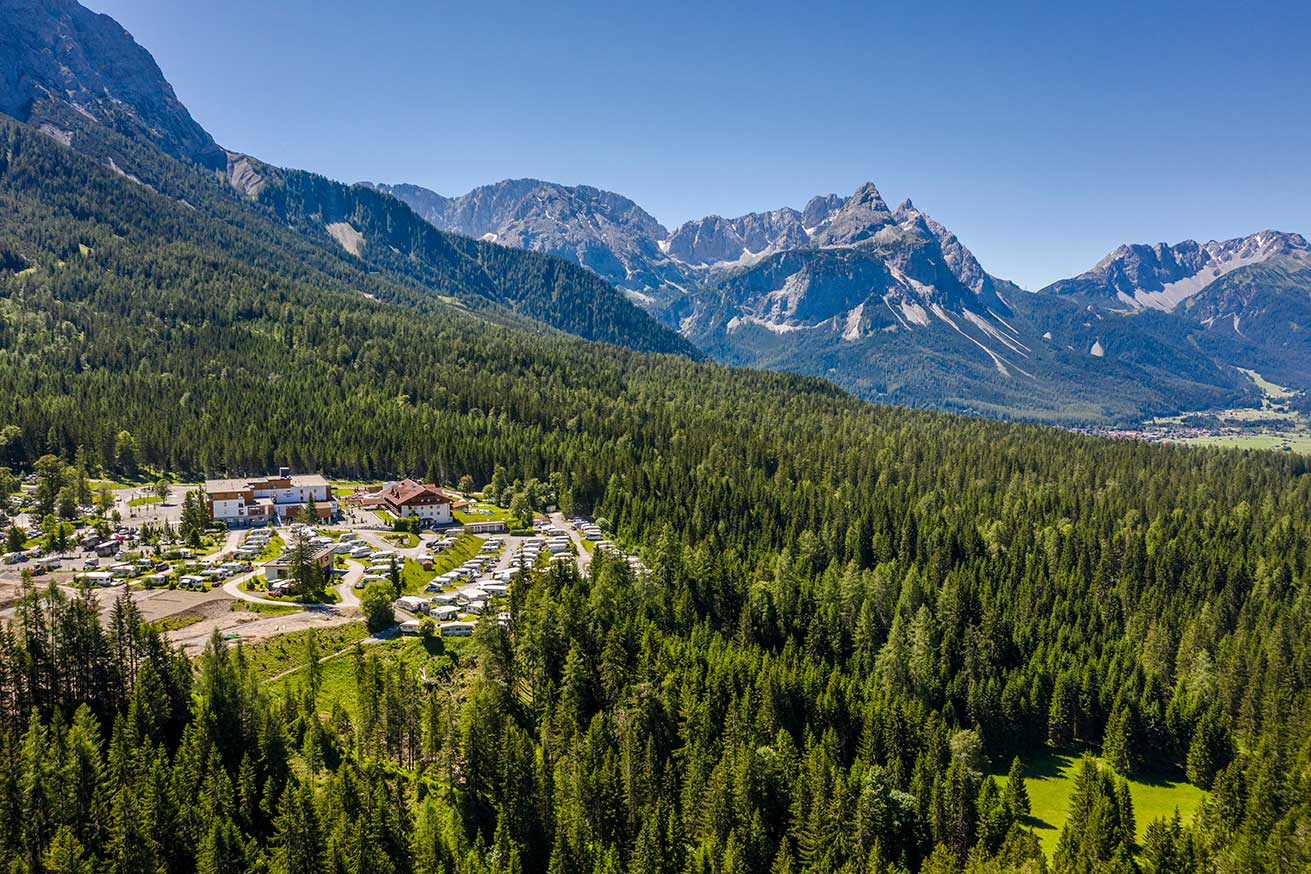 Campingplatz umgeben von Wald und Bergen