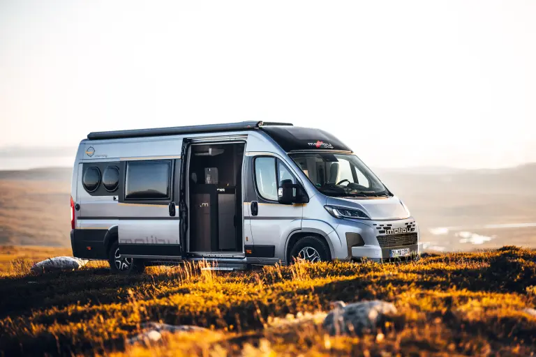 Seitenansicht eines Malibu Campervans inmitten einer baumlosen, steinigen herbstlichen Landschaft.