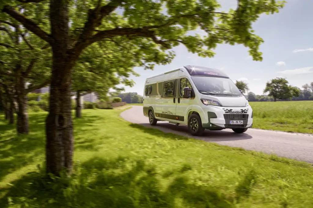 Malibu Campervan first-class-two-rooms auf einer naturumgebenden Landstraße.