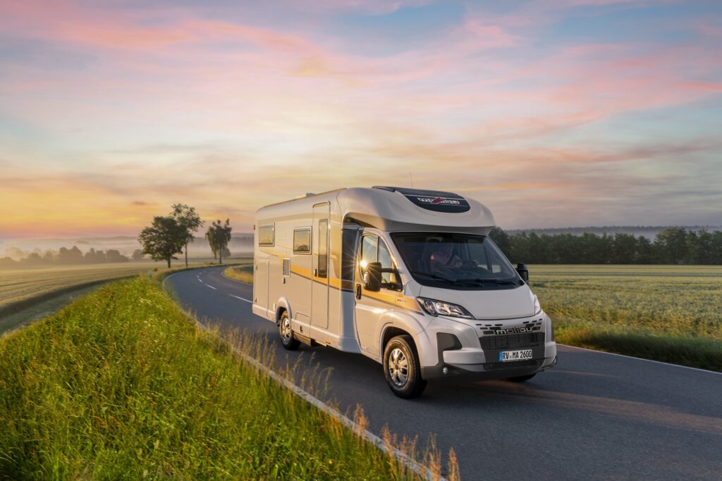 Malibu Reisemobil Teilintegriert fährt auf einer schönen Landstraße bei Sonnenuntergang.