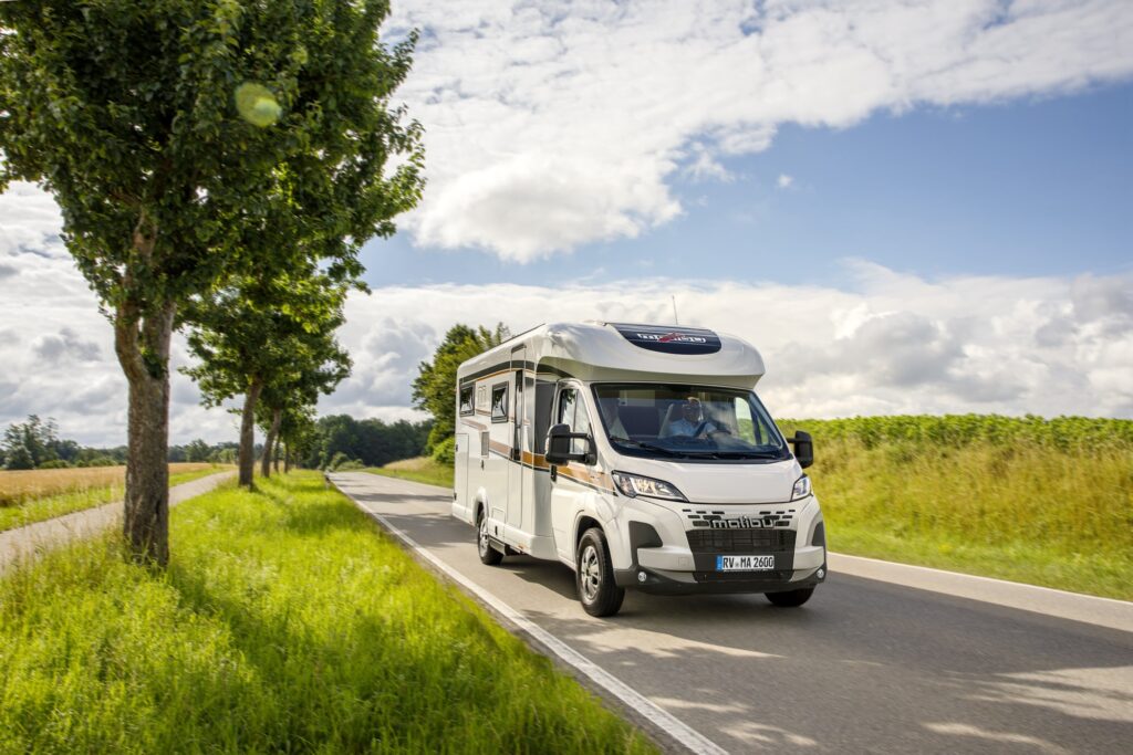 Malibu Reisemobil Teilintegriert fährt auf einer Landstraße.