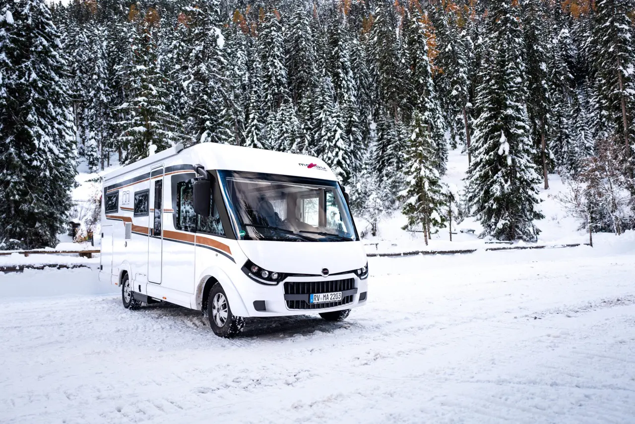 Malibu Reisemobil inmitten von Schnee und verschneiten Bäumen.