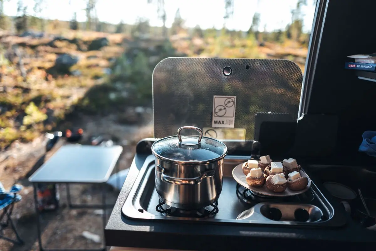 Ansicht der Küche eines Malibu Van mit einem Kochtopf und vorbereiteten Pilzen für den Grill.